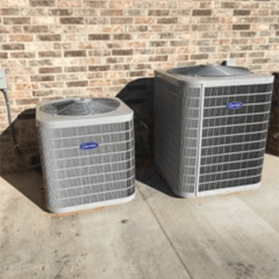 light grey hvac boxes outside of a bricked walled house with a concrete floor